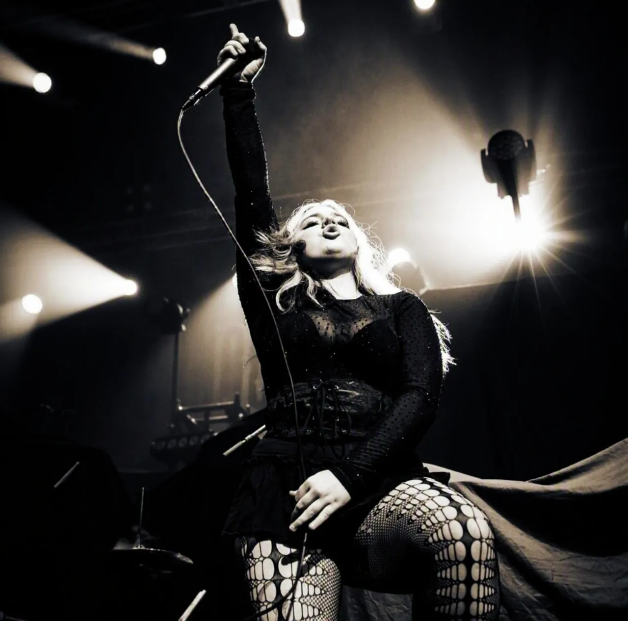 Madison Moon singing live on stage under spotlights, arm raised with microphone in hand - rock and hard-rock vocalist and American Idol Top 20 finalist (2026)